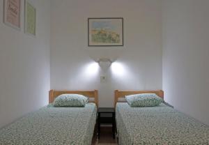 two beds in a room with white walls at Studio Apartment Michelle - Intermezzo with sea view in Rabac