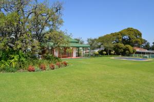 un parque con un edificio y un césped verde en Lekkerrus guesthouse en Krugersdorp