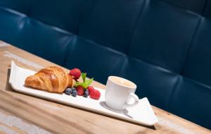 a plate with a croissant and berries and a cup of coffee at Renaissance Newport Beach Hotel in Newport Beach