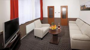 sala de estar con sofá, TV y mesa en Pension-Restaurace Lugano, en Hřensko