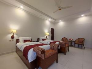 um quarto de hotel com duas camas e duas cadeiras em Welcome Hotel Islamabad em Islamabad