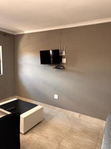 a living room with a tv on the wall at Platinum Guesthouse Kempton park in Kempton Park