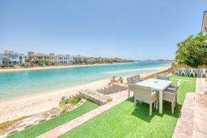 ein Tisch und Stühle auf dem Gras in Strandnähe in der Unterkunft Stunning Villa with Private Pool & Beach Access in Dubai