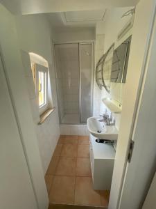 a white bathroom with a sink and a mirror at Ferienhaus Weißburgunder am Weinberg in Naumburg