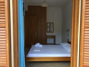 1 dormitorio con cama blanca y cortina azul en Niko's Apartments A1 en Gialiskari