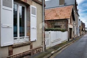 un edificio con puertas y ventanas blancas en una calle en Le Villervillais CLS Deauville en Villerville