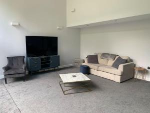 a living room with a couch and a flat screen tv at 3 bedroom barn conversion in the country (Pet Friendly) in Stawell