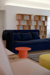 uma sala de estar com um sofá azul e uma mesa vermelha em BasicVillage Milano em Milão