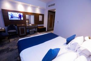 een hotelkamer met een groot bed en een televisie bij The Guard Hotel in Caïro