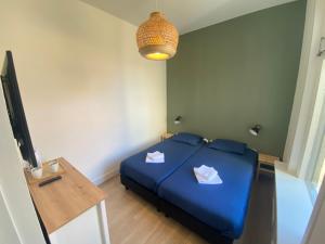 ein Schlafzimmer mit einem blauen Bett und einem TV in der Unterkunft Hotel 't Sonnehuys in Scheveningen