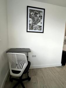 a desk with a chair and a picture on a wall at Luxurious City View Apartment in Salford in Manchester