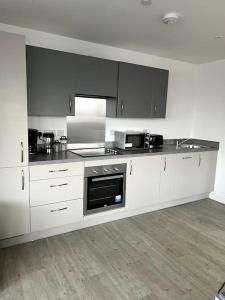 a kitchen with white cabinets and a stove top oven at Luxurious City View Apartment in Salford in Manchester