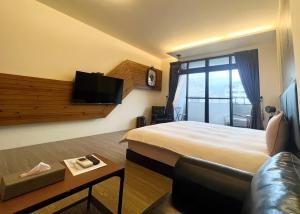 een hotelkamer met een bed, een tv en een bank bij 秋合民宿 in Hualien