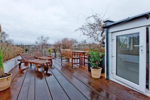 une terrasse en bois avec des bancs et une table dans l'établissement 4 Bed Duplex Garden Views, à Londres