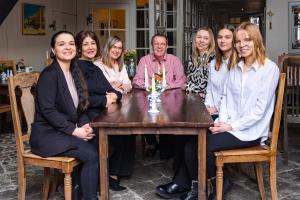 un grupo de personas sentadas alrededor de una mesa de madera en Hotel Haase en Lübeck