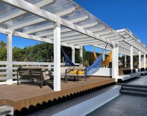 a pergola with chairs and hammocks on a deck at Herdade do Kuanza in Zambujeira do Mar