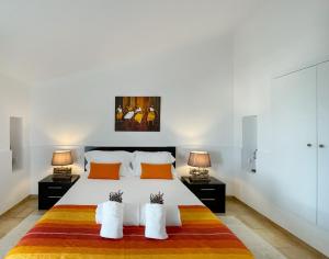 a bedroom with a large white bed with two lamps at Herdade do Kuanza in Zambujeira do Mar