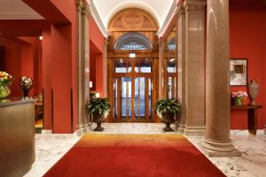 un hall aux murs rouges et une porte avec un tapis rouge dans l'établissement Hotel L'Orologio Roma - WTB Hotels, à Rome