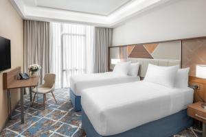 a hotel room with two beds and a desk at Three Points Musalli Makkah in Mecca