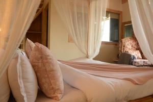 Schlafzimmer mit einem Bett mit weißen Vorhängen und einem Stuhl in der Unterkunft Musafir cottage in Pālampur