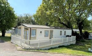 a small white house with a white fence at Sea Breeze a beautiful 3 bedroom coastal caravan in Milford on Sea