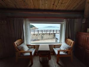 een kamer met 2 stoelen, een tafel en een groot raam bij Horn Seaside Homestay in Nangan