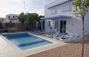 a villa with a swimming pool in front of a house at Villas Calan Bosch Mar in Cala en Bosc