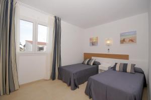 a bedroom with two beds and a window at Villas Calan Bosch Mar in Cala en Bosc