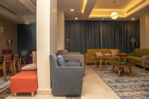 a living room with couches and chairs and tables at Durrat Manzli ApartHotel in Al Khobar