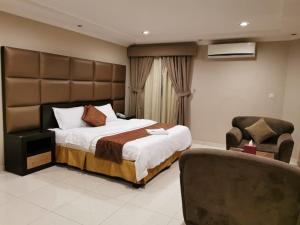 a bedroom with a large bed and a chair at Ashbonh Hotel Suites in Riyadh