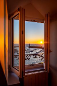 une fenêtre avec vue sur l'océan et le coucher du soleil dans l'établissement Hotel Atlantique, au Palais