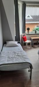 ein Schlafzimmer mit einem Bett mit einem roten Kissen darauf in der Unterkunft Soucis au vent in De Panne