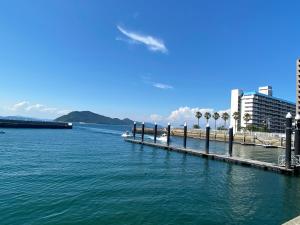 ein großer Wasserkörper mit einem Pier und Palmen in der Unterkunft 浜町小院 Guest House in Takamatsu