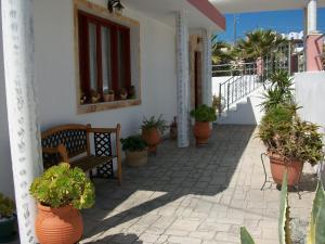 a porch with a bench and potted plants at Villa Koronios in Fira