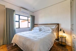 1 dormitorio con 1 cama con sábanas blancas y ventana en Bali and Eva Midlands, en Nottingham Road