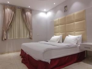 a bedroom with a large bed with white sheets and pillows at العرين بارك للشقق المخدومة in Abha