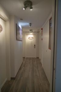 un couloir vide avec des murs blancs et du parquet dans l'établissement Hotel Bella Dolores, à Lloret de Mar