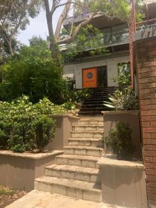 a set of stairs leading to a building with an orange door at Tranquil Garden Studio in Wollongong