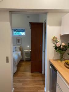 een slaapkamer met een bed en een vaas met bloemen bij Tranquil Garden Studio in Wollongong