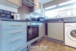 cocina con armarios azules, lavadora y secadora en Briscoe Serviced Accommodation en Mánchester