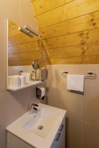 La salle de bains est pourvue d'un lavabo blanc et d'un miroir. dans l'établissement Alpska kuća Lucy, à Jasenak