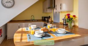 a kitchen with a wooden table with food and glasses of orange juice at Cambridge Stays Diamond 2BR Apartment-Central-Parking-Walk to city & train station in Cambridge