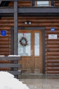 Alpska kuća Lucy في Jasenak: باب كوخ خشبي عليه اكليل