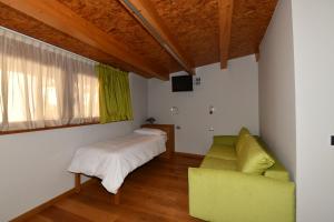 a bedroom with a bed and a couch and a window at Agritur Anselmi in Terzolas