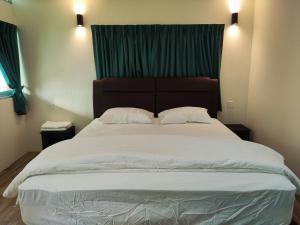 1 cama grande en un dormitorio con cortina verde en Rainbow Huts by Zing Motel, en Butterworth