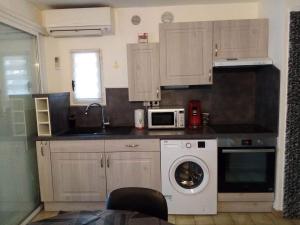 a kitchen with a washing machine and a microwave at Zenatitude in Marseillan