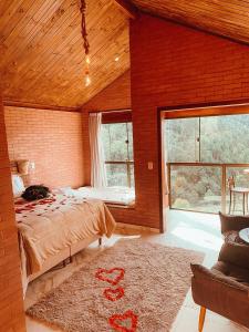 a bedroom with a large bed and a large window at Vila Italliana Chalés - Chalé Veneza in Santa Teresa