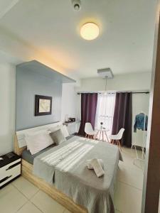 a bedroom with a large bed and a table at Tagaytay Nordic Nest Staycation at Wind Residences with Netflix Wifi near Sky Ranch in Tagaytay