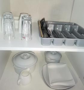 a white shelf with dishes and utensils at Angie's Nest in East London