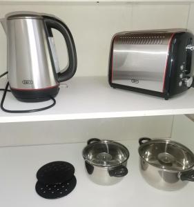 a toaster and two pots and pans on a shelf at Angie's Nest in East London